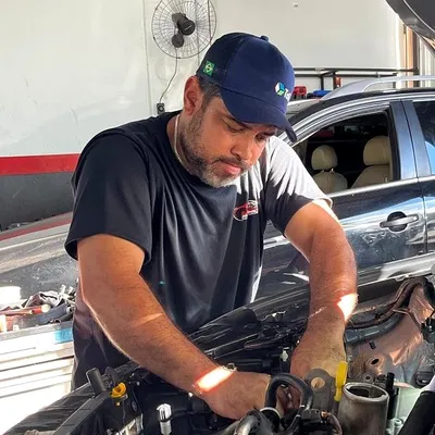 José Luiz, proprietário da JL Mecânica, trabalhando no motor de um veículo na oficina